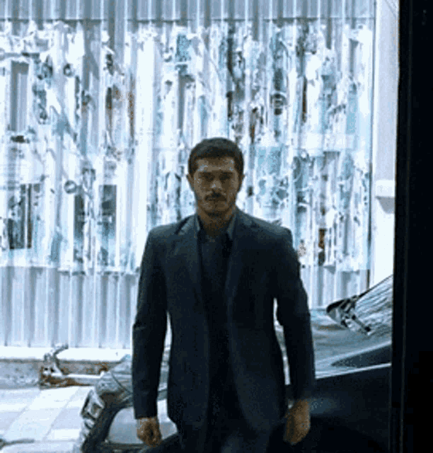 a man in a suit is standing next to a black car