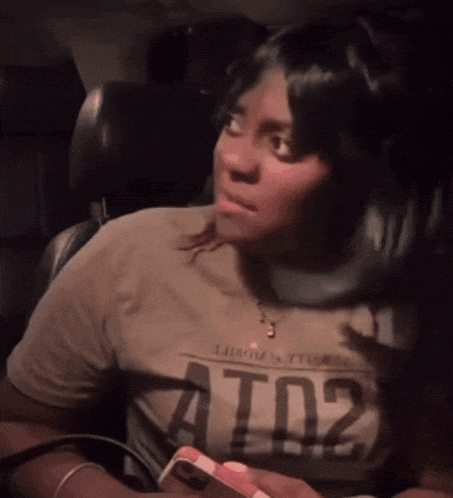 a woman sitting in a car wearing a t-shirt that says t02