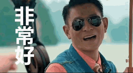 a man wearing sunglasses and a denim vest is holding a fishing rod .