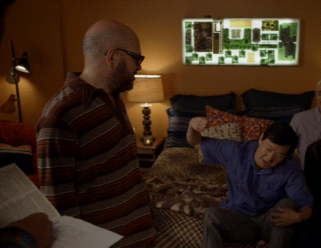 a man in a striped shirt is standing next to another man in a bedroom