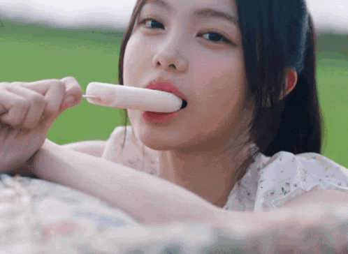 a young woman is eating a popsicle with her tongue out