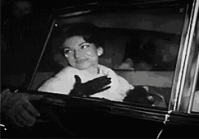 a black and white photo of a woman looking out a car window