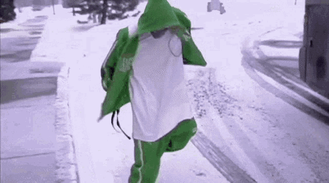 a person wearing a green jacket and white pants is running in the snow .