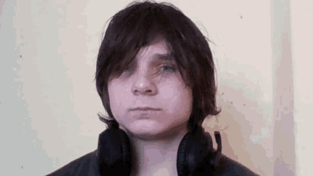 a young boy wearing headphones looks at the camera .
