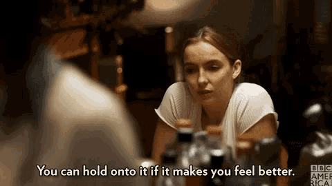 a woman is sitting at a table with a bunch of bottles of alcohol and talking to a man .