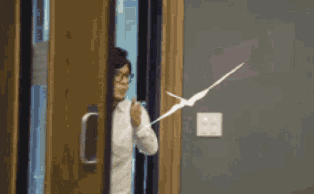 a woman with glasses is standing in a doorway with a drawing of an arrow on the wall