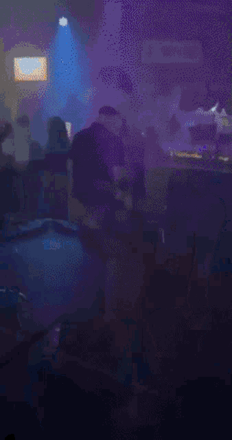a blurry picture of people dancing in a dark room with blue lights