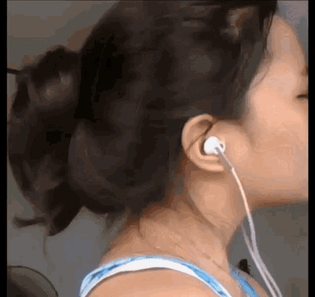 a close up of a woman wearing ear buds and a bun .