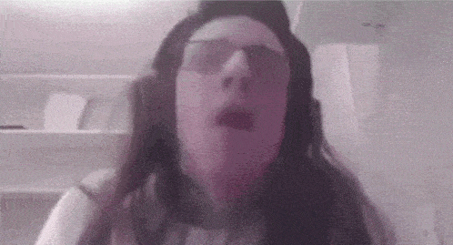 a woman wearing headphones and glasses is making a face .