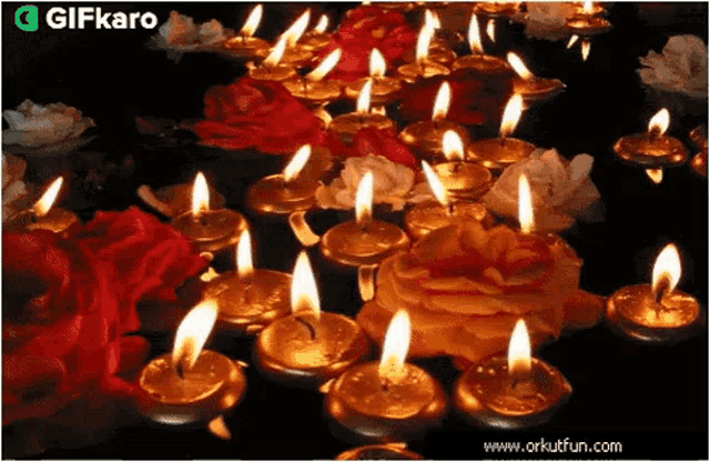 a bunch of lit candles surrounded by flowers with a gifkaro logo in the corner