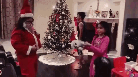 a woman dressed as santa claus is talking on a cell phone next to a christmas tree .