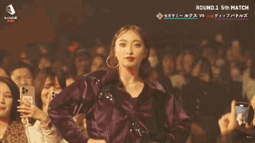 a woman stands in front of a crowd with the name marin on the bottom right