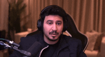 a man wearing headphones is sitting in front of a microphone in a chair .