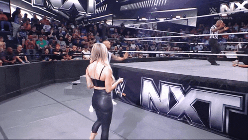 a woman stands on a stage in front of a nxt sign