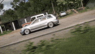 a silver car is driving down a road next to a building