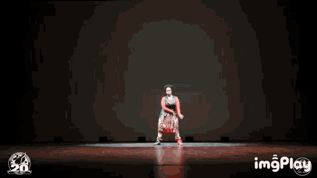 a person is dancing on a stage with a 20th anniversary logo in the background