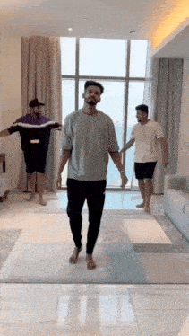 a group of men are standing in a living room holding hands