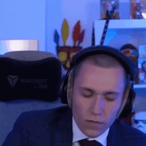 a man in a suit and tie is wearing headphones and a pillow that says secret lab