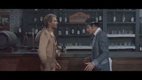 two men are standing in front of a bar with a sign that says no spitting allowed