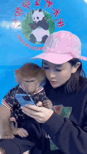 a woman wearing a pink ny hat is holding a monkey