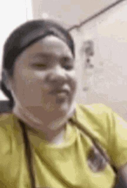 a close up of a woman wearing a yellow shirt and a mask .
