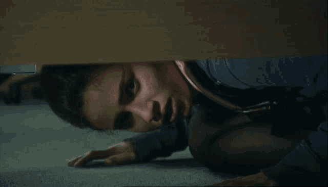 a woman is crawling under a desk with a shocked look on her face