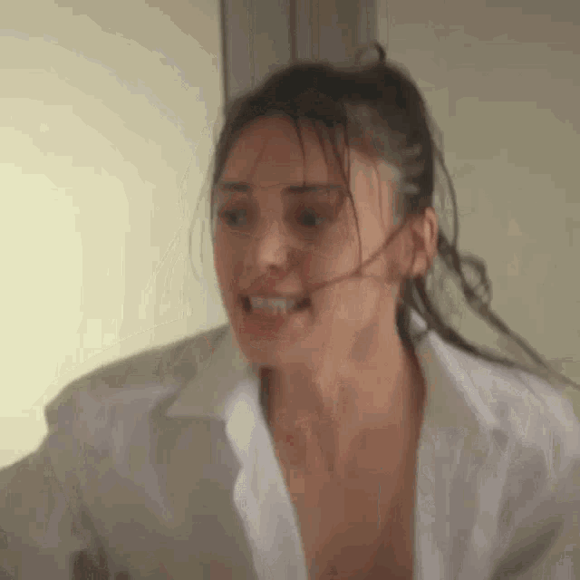 a woman in a white shirt is making a funny face and looking at the camera .