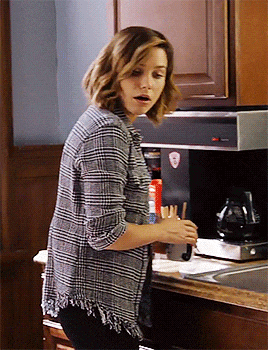 a woman wearing a plaid shirt is standing in a kitchen