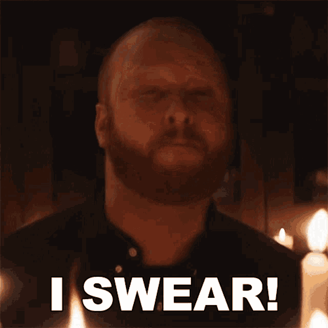 a man with a beard is saying " i swear " in front of candles .