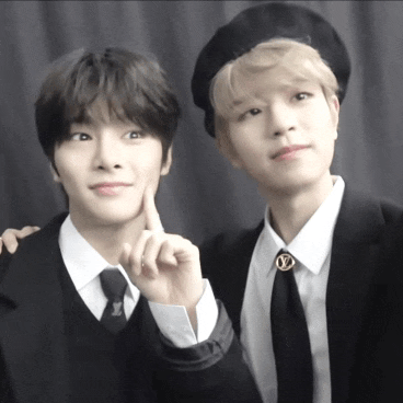 two young men are posing for a picture and one is wearing a louis vuitton brooch