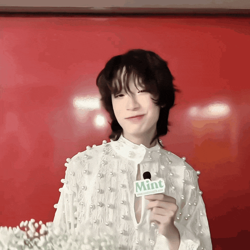 a person holding a microphone with a mint sign on it