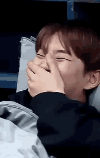 a young man is covering his mouth with his hand while laughing .