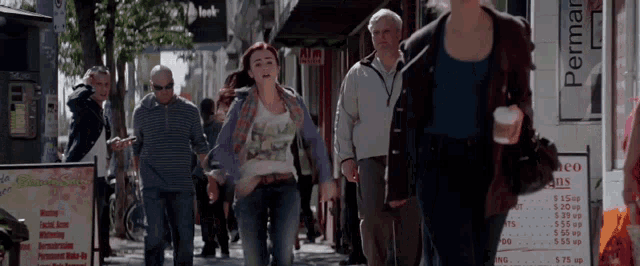 a woman walking down a street with a sign that says permanent
