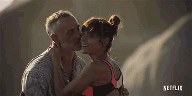 a man kisses a woman on the cheek with a netflix logo in the corner