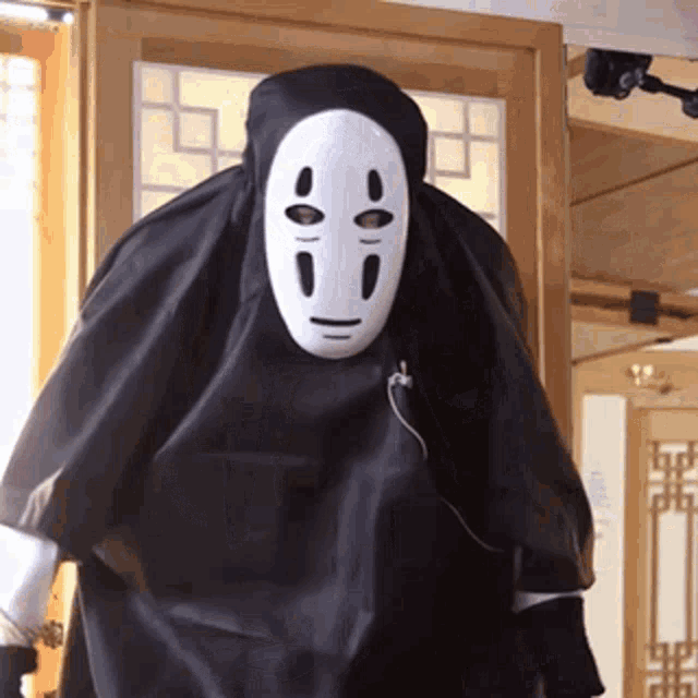 a person wearing a black cape and a white face mask