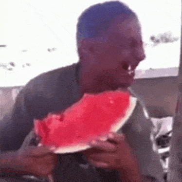 a man is eating a slice of watermelon with a knife .