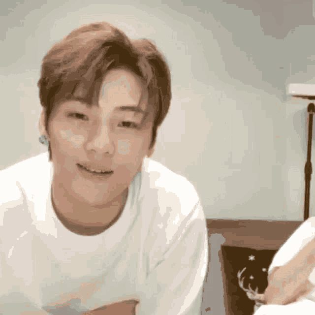 a young man wearing a white shirt is smiling