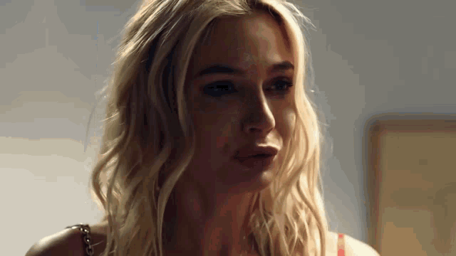 a close up of a woman 's face with blonde hair and a red bra
