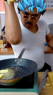 a man in a white shirt is cooking in a frying pan with tiktok written on the bottom of the screen