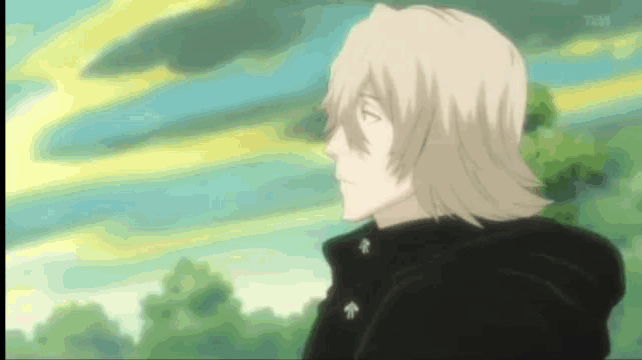 a man with blonde hair and a black jacket is standing in a field with trees in the background .