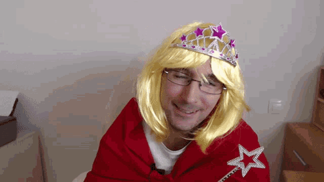 a man wearing a red cape and a yellow wig has a tiara on his head