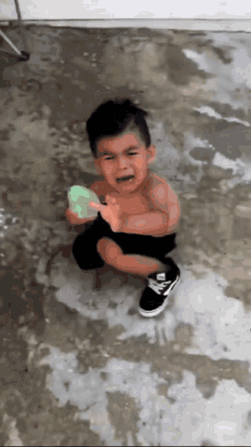 a little boy is crying while holding a water gun .