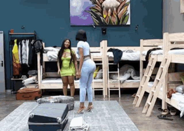 two women are standing in front of bunk beds in a dorm room .