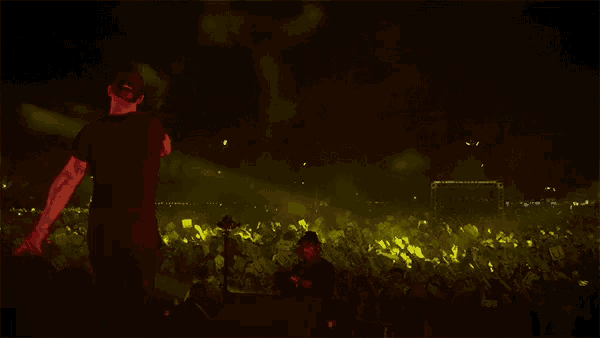 a man singing into a microphone in front of a crowd of people