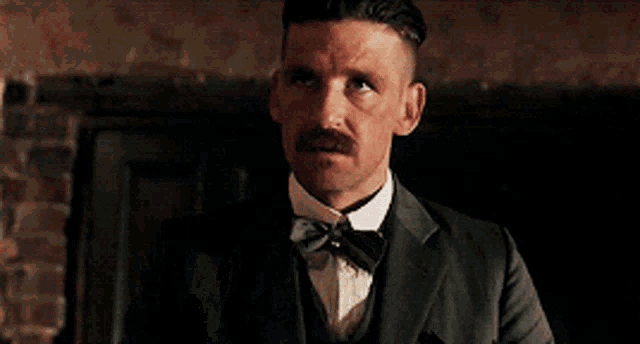 a man in a suit and bow tie is drinking from a bottle