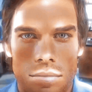 a close up of a man 's face with a blue shirt