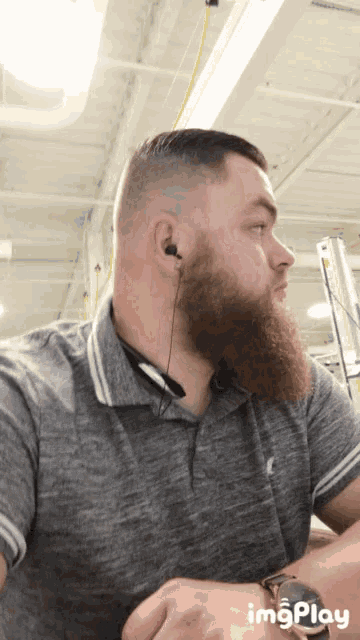 a man with a beard wearing a watch and ear buds