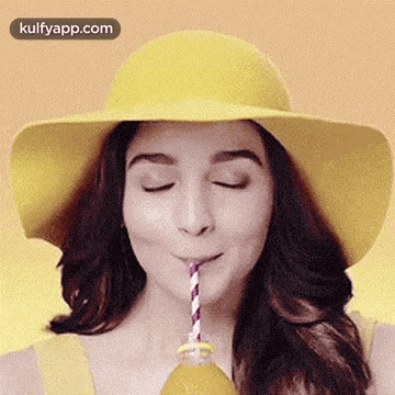a woman in a yellow hat is drinking from a straw .