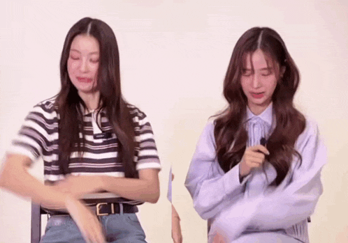 two young women are sitting next to each other and one is crying