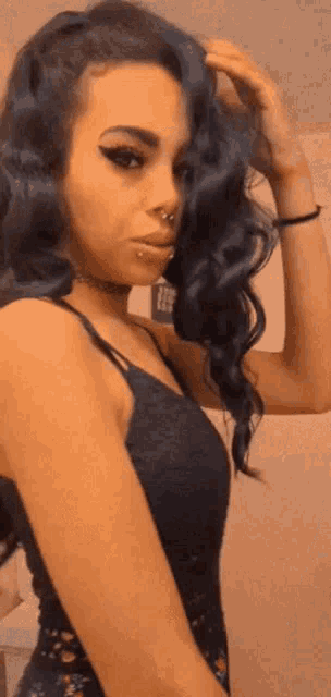 a woman with blue hair is wearing a black tank top and a nose ring